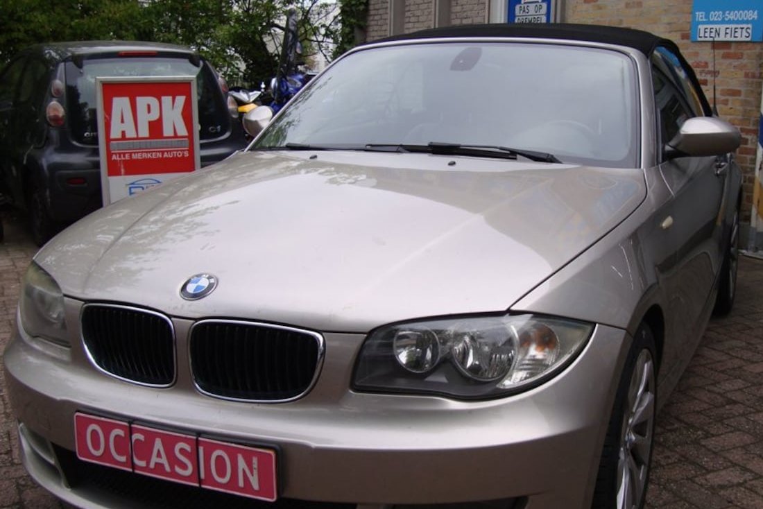 Het APK-bord aan de gevel van Garage Rapid, met een occasion ervoor