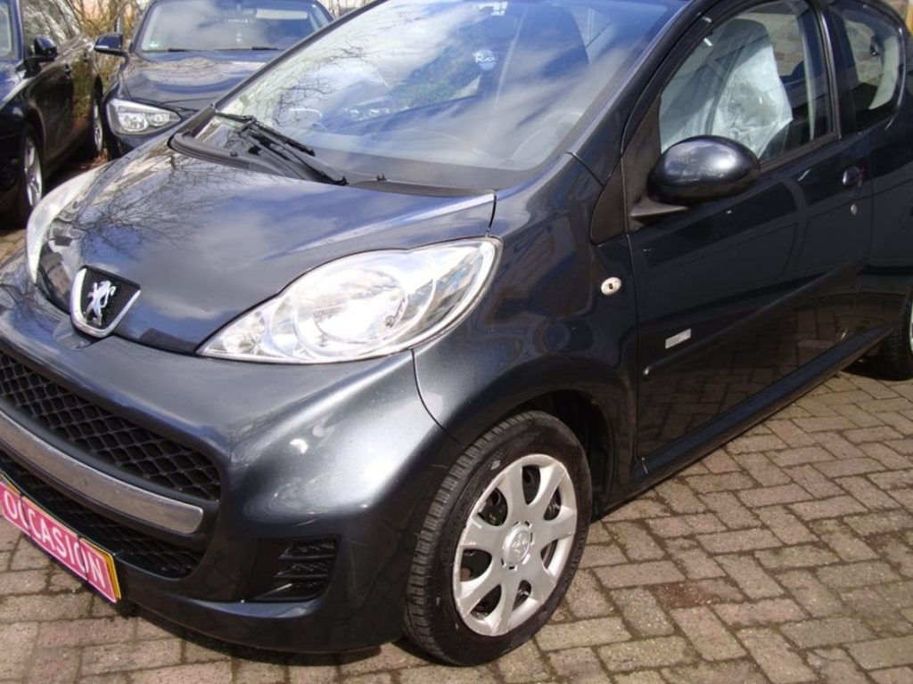 Donkergrijze Peugeot 107 voor de deur bij Garage Rapid in Haarlem