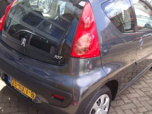 Donkergrijze Peugeot 107 voor de deur bij Garage Rapid in Haarlem