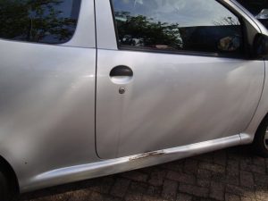 Zilvergrijze Toyota Aygo voor de garagedeuren van Garage Rapid